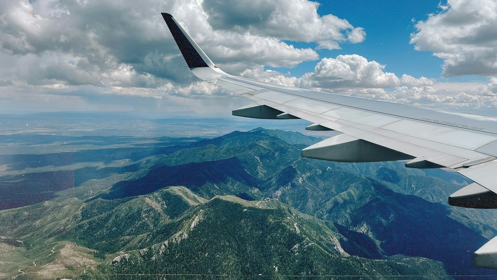 Airplane wing in flight over a mountain range