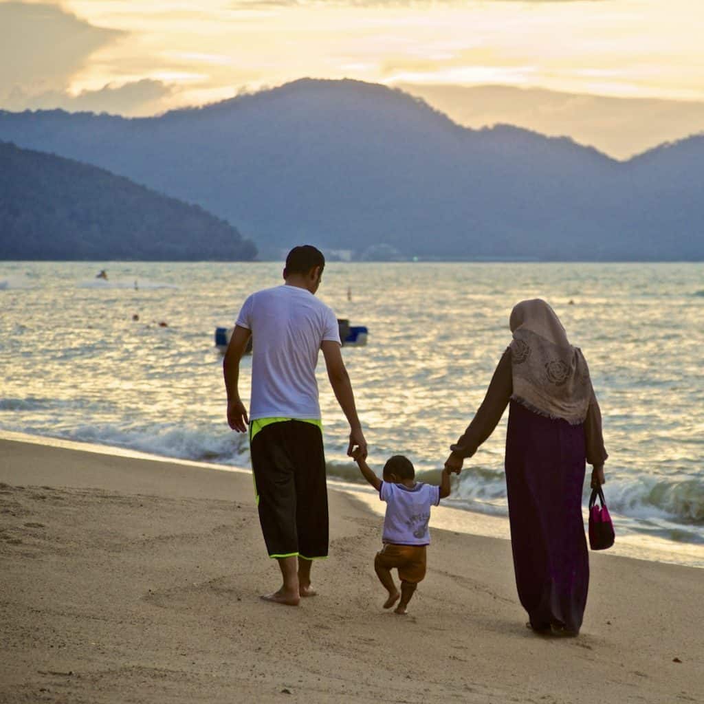 Muslim family walking on a beach at sunset