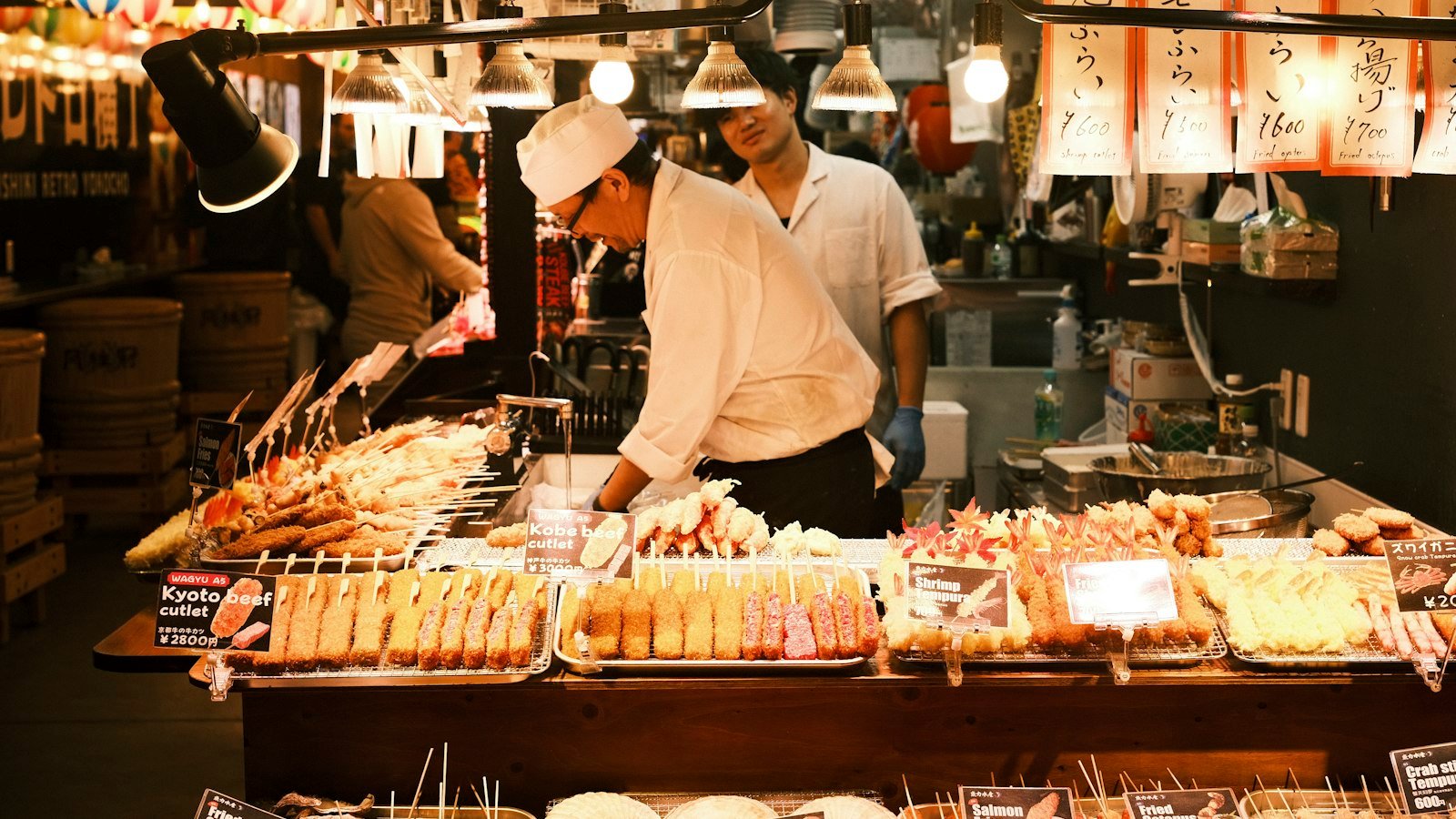 Vendors selling skewers at a busy Japanese food market