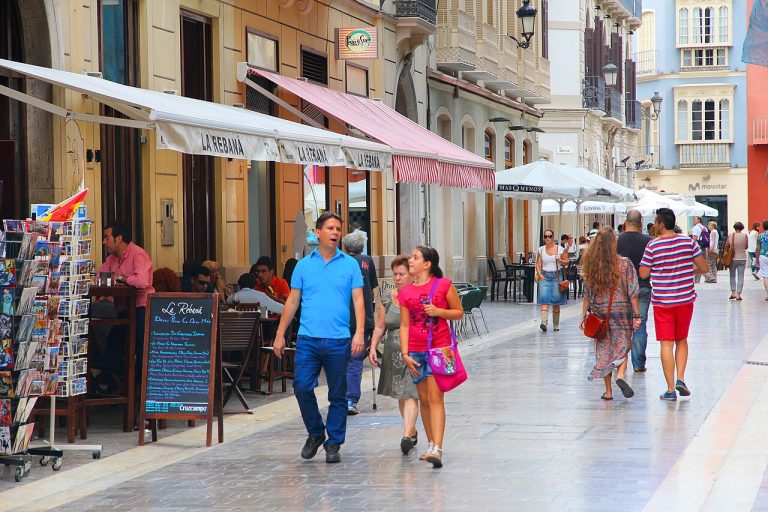 Visitors walking along a shopping street in Málaga's Centro Histórico, Spain