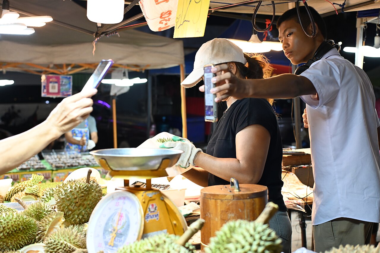 A customer pays by phone at a night market stall in Sattahip, Thailand