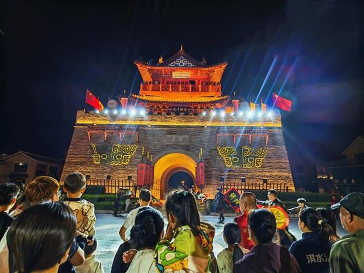 Visitors watch a night-time show at an illuminated gate tower in Qi County, Henan Province, China