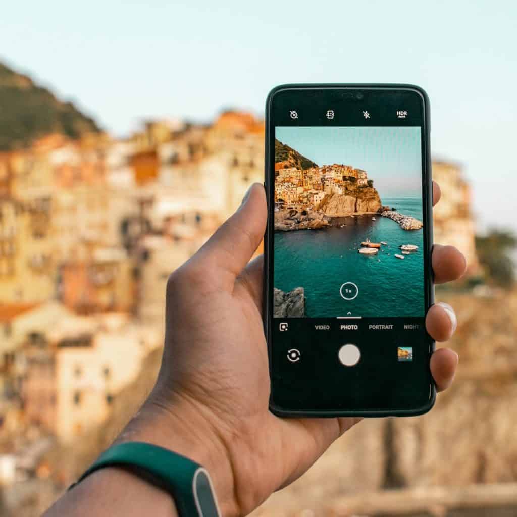 Traveller photographing a coastal village on a smartphone